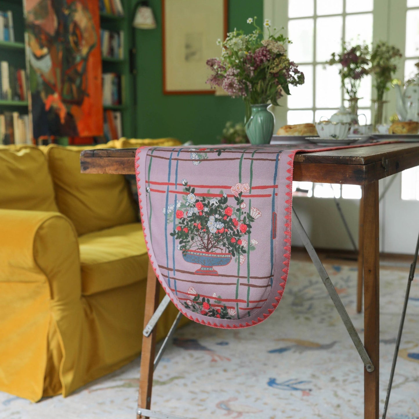 Decorative table runner with floral design on a wooden table in a cozy room.