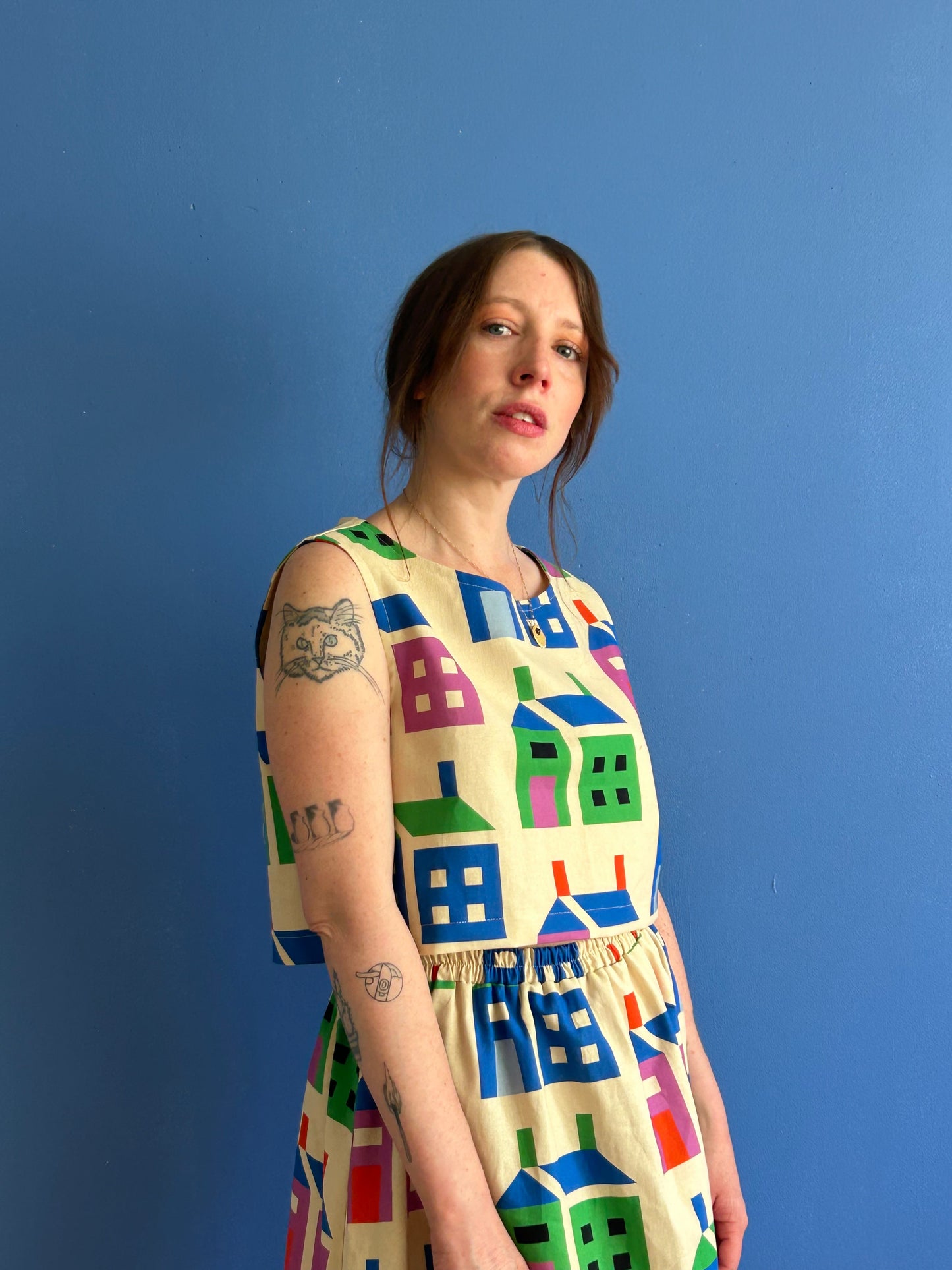 Woman wearing a colorful dress with house pattern against a blue background