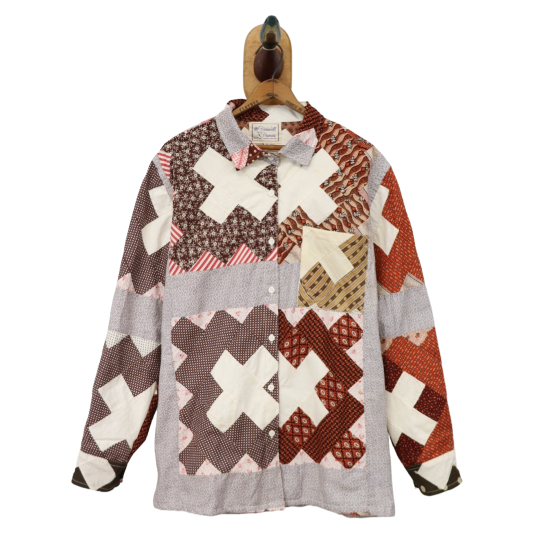 Patchwork shirt with cross pattern on a hanger against a white background