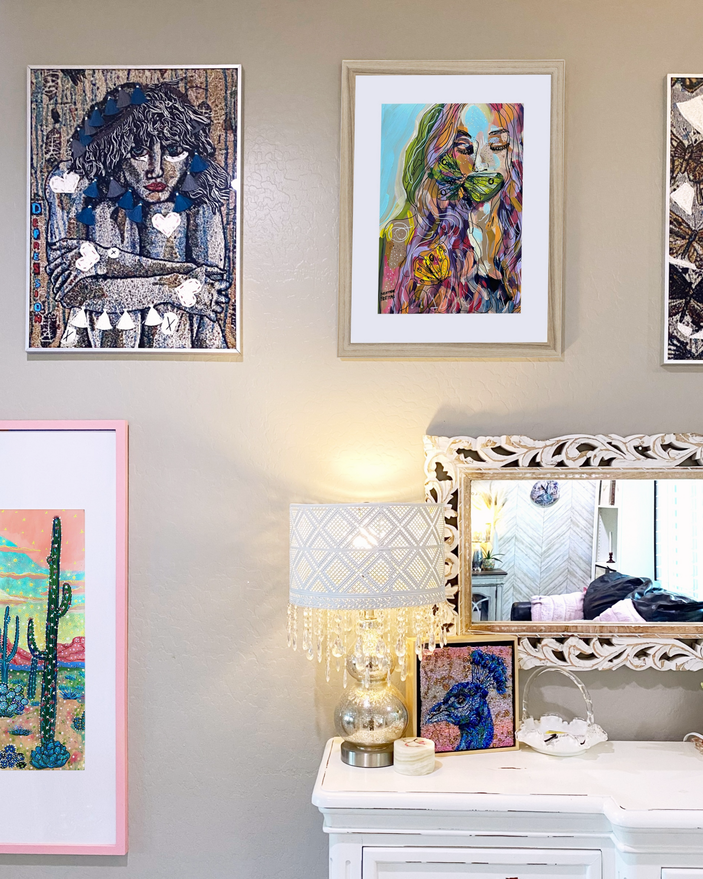 Wall with framed artwork and a mirror reflecting a room.