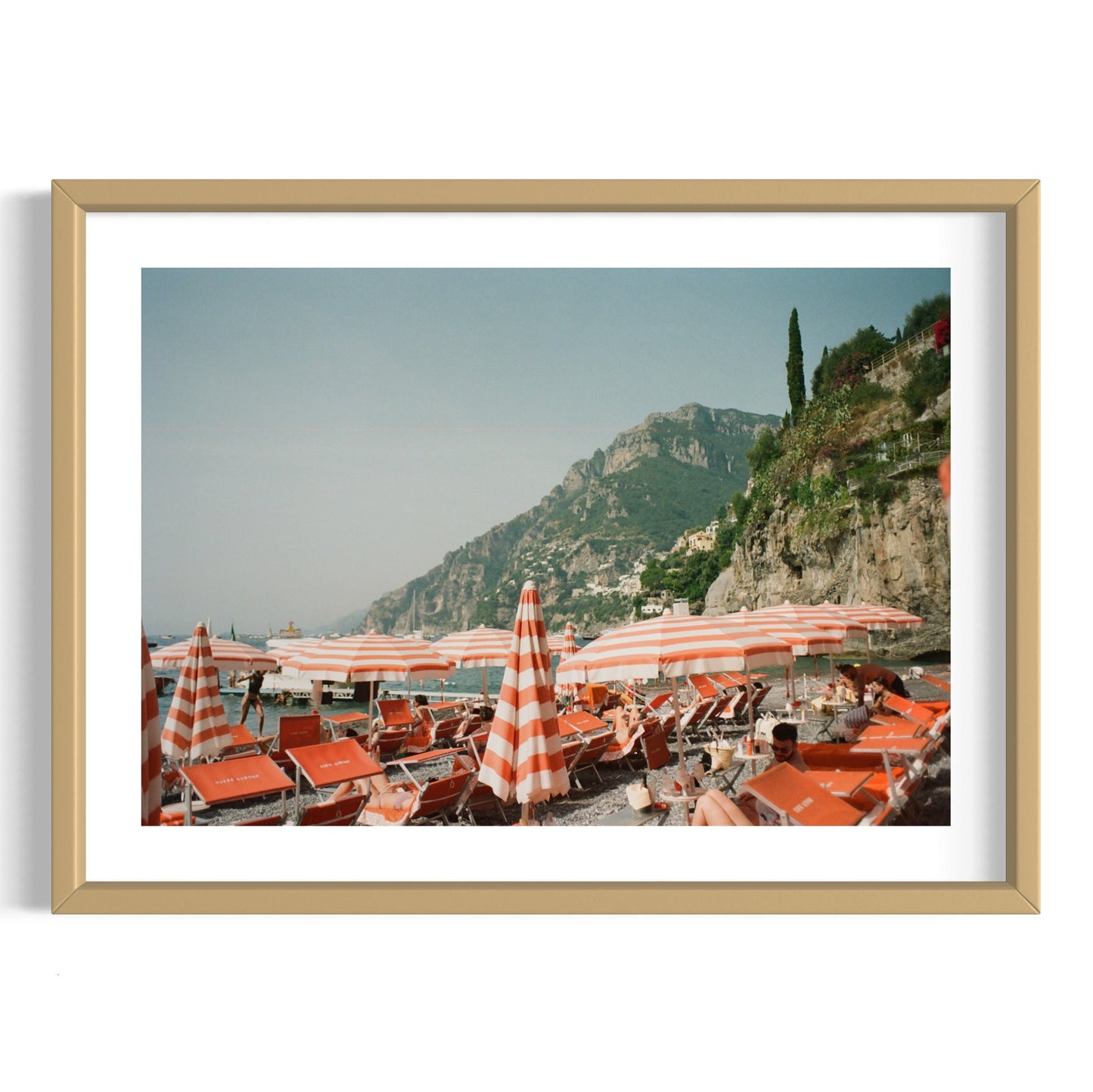 Framed photograph of a coastal scene with striped umbrellas and lounge chairs.