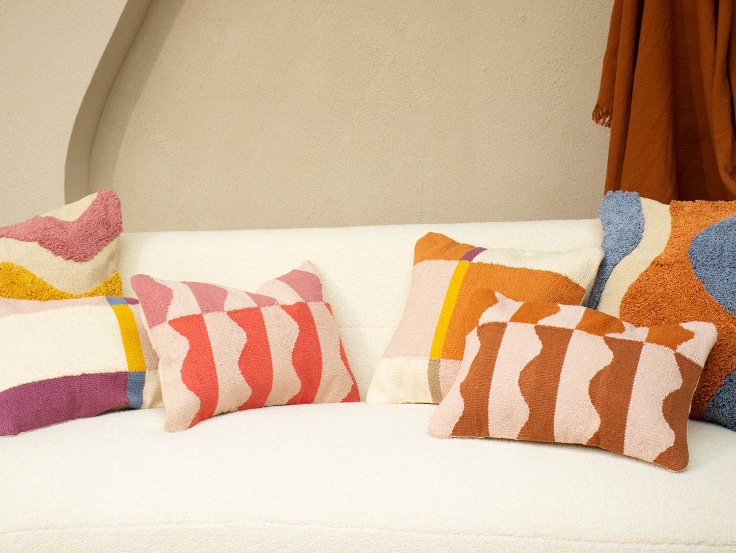 Colorful patterned cushions on a white sofa against a beige wall.