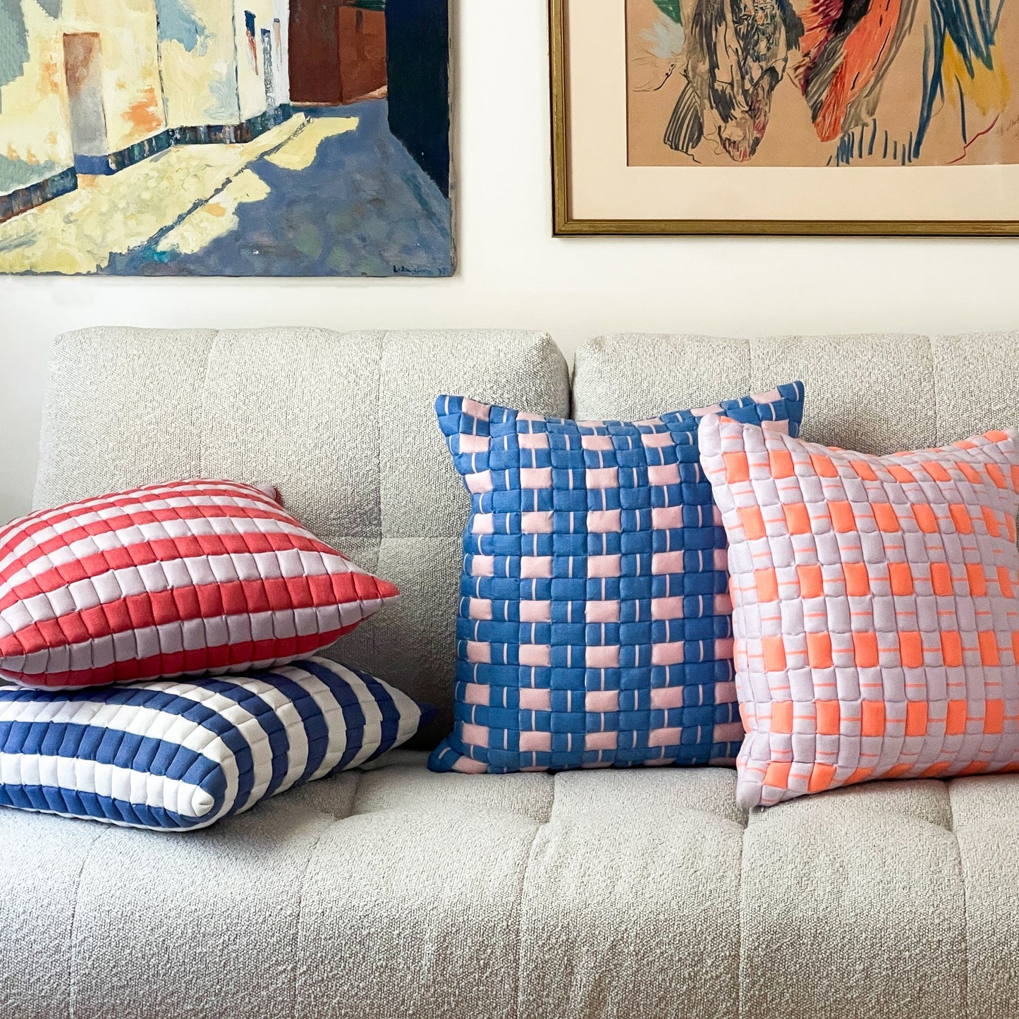 Colorful pillows on a beige sofa with abstract art in the background
