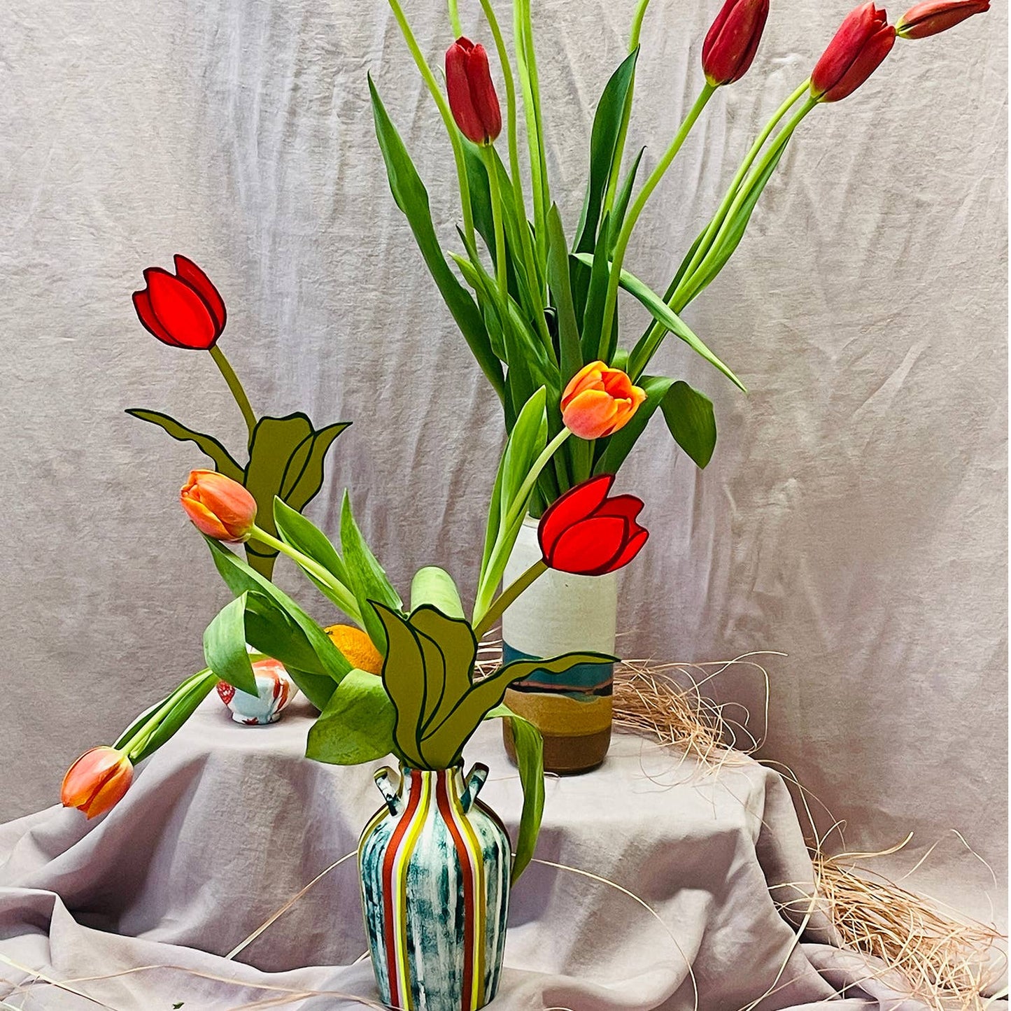 Colorful tulips in a striped vase on a textured surface