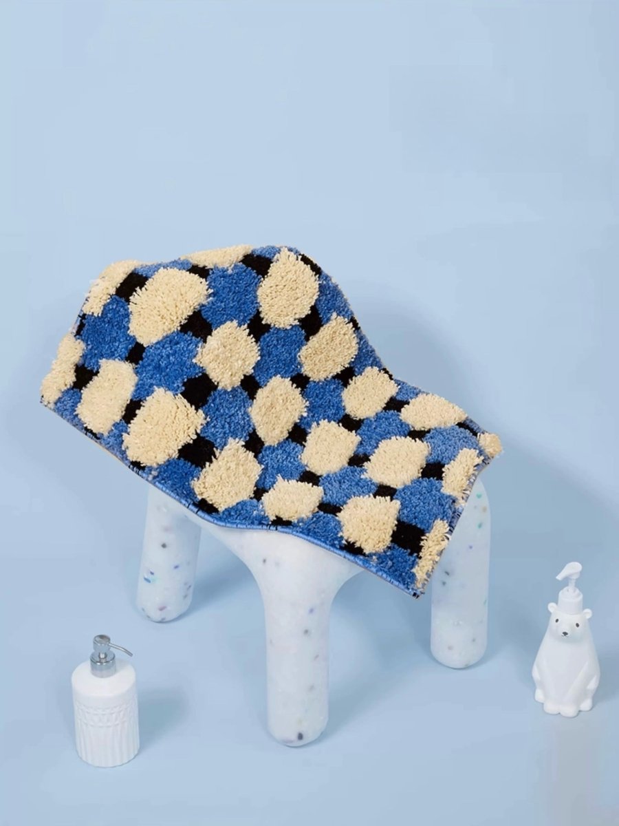 Small stool with a checkered blue and beige cushion on a light blue background