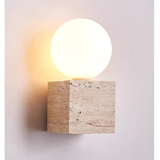 Wall-mounted light fixture with a stone base and round glass cover on a neutral background