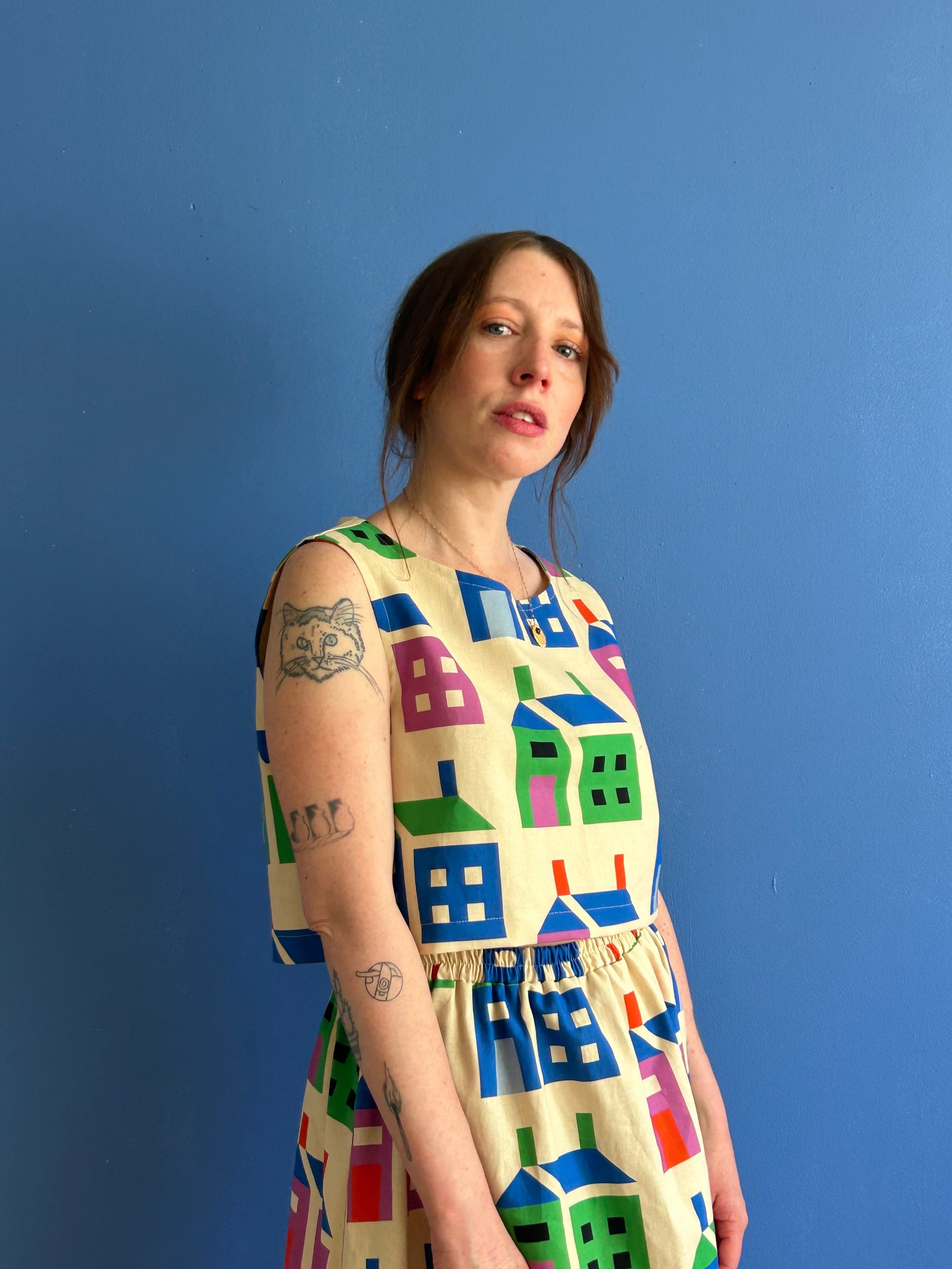 Woman wearing a colorful dress with house pattern against a blue background