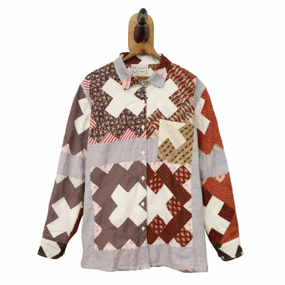 Patchwork shirt with cross pattern on a hanger against a white background
