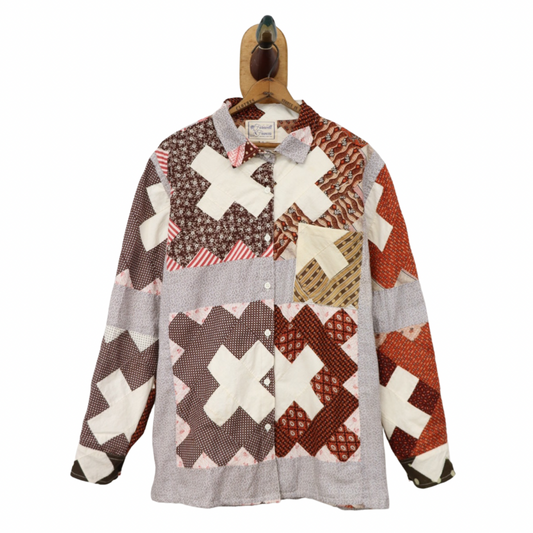 Patchwork shirt with cross pattern on a hanger against a white background