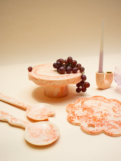 Decorative items including a wooden stand with grapes, cookies, and a candle on a beige surface.