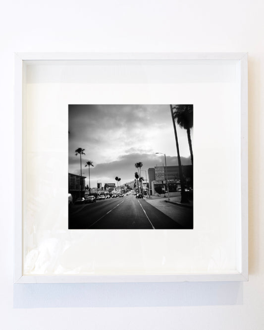 Framed black and white photograph of a city street with palm trees.