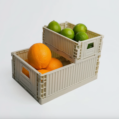 Two beige crates with oranges and limes on a white background
