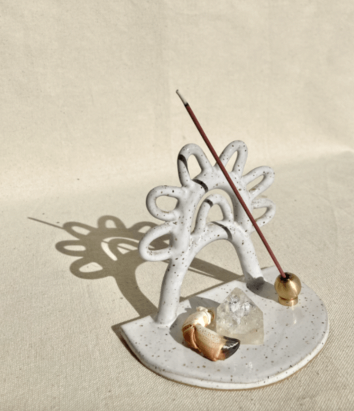 White ceramic incense holder with a leaf design on a beige background