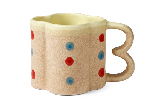 Beige mug with red and blue polka dots on a white background