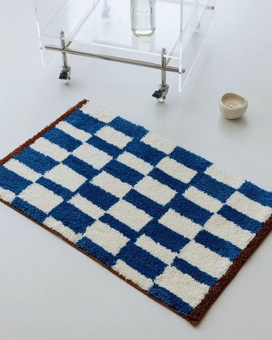 Blue and white checkered bath mat on a bathroom floor.